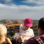 Smiling family with children exploring a traditional Chinese garden with red lanterns and pagodas.