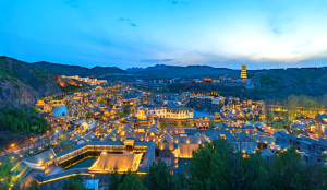 Canal view of Gubei Water Town with lantern-lit bridges and Simatai Great Wall in the background