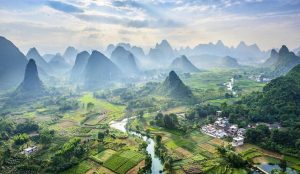 Dramatic karst mountain peaks rising above the Li River near Guilin, with bamboo rafts floating downstream.