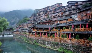 Ethnic Miao village nestled in the green hills of Guizhou, with wooden stilt houses and traditional costumes.