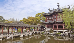 A classical Chinese garden with traditional architecture and a nearby bustling marketplace.