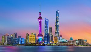 Skyline of Shanghai with the Oriental Pearl Tower and modern skyscrapers along the Huangpu River at sunset.