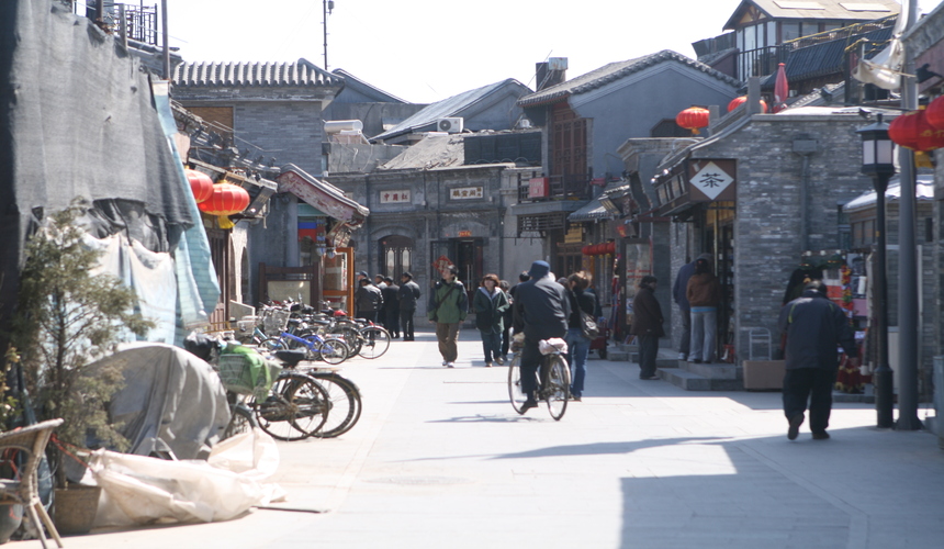 Narrow alleyway of a traditional Beijing hutong lined with old courtyard houses.