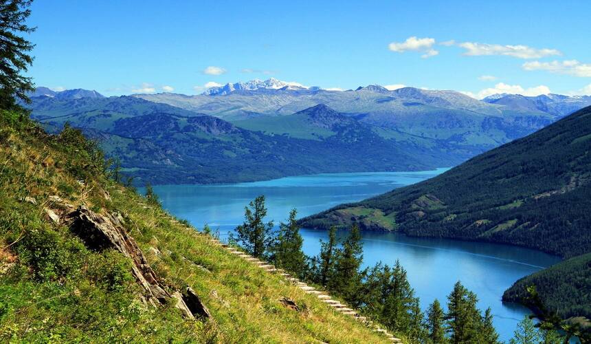 Traveler horseback riding through alpine meadows in Kanas, Xinjiang