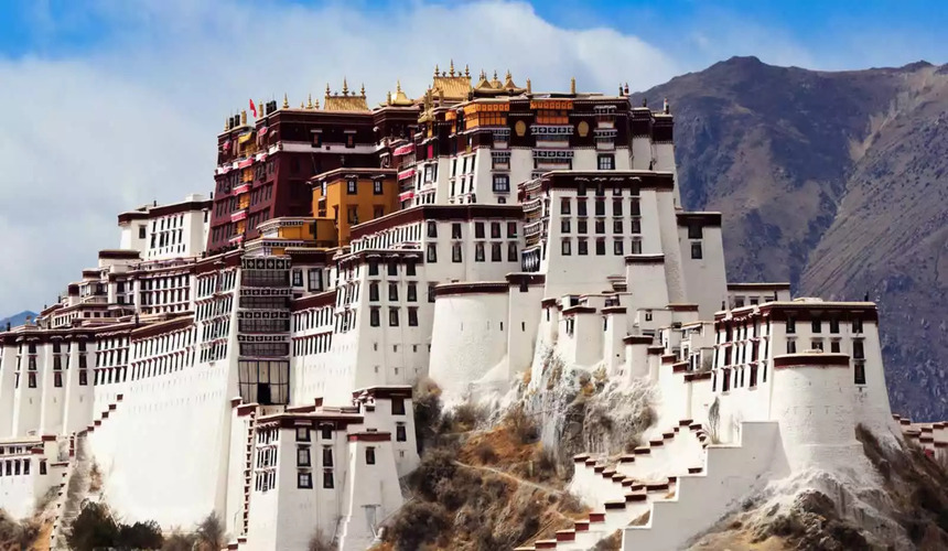 Majestic Potala Palace perched on a hill in Lhasa, Tibet, with blue sky and clouds in the background.