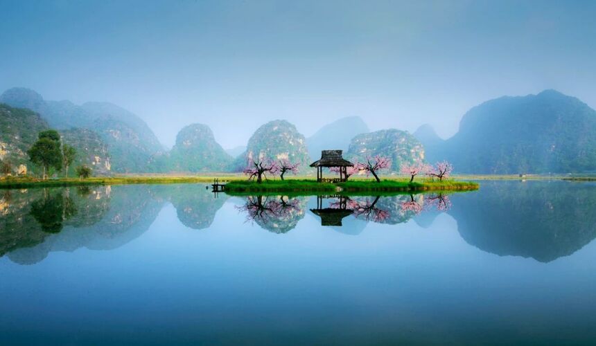 Tranquil lake surrounded by green hills and lotus flowers at Puzhehei Scenic Resort in Yunnan.