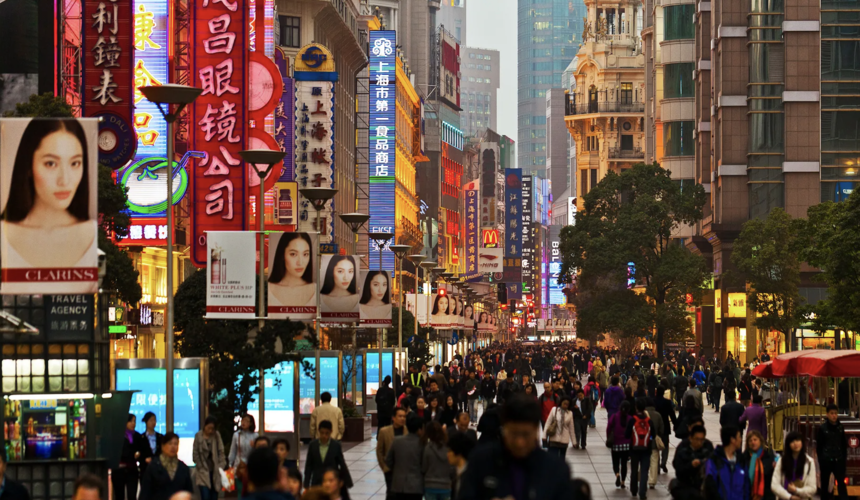 Bustling Nanjing Road in Shanghai filled with shops, lights, and crowds of shoppers.