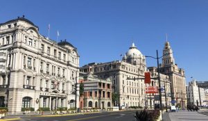 Historic colonial buildings along the Bund in Shanghai with a view of Pudong skyline across the river.