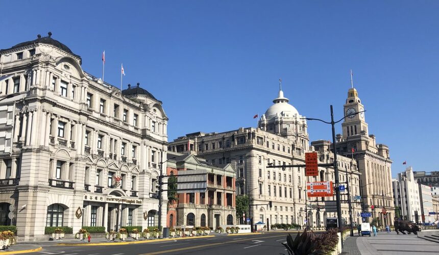 Historic colonial buildings along the Bund in Shanghai with a view of Pudong skyline across the river.