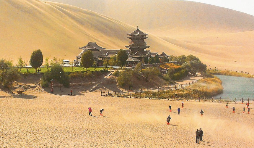 Camel caravan crossing desert dunes on the Silk Road in China at sunset