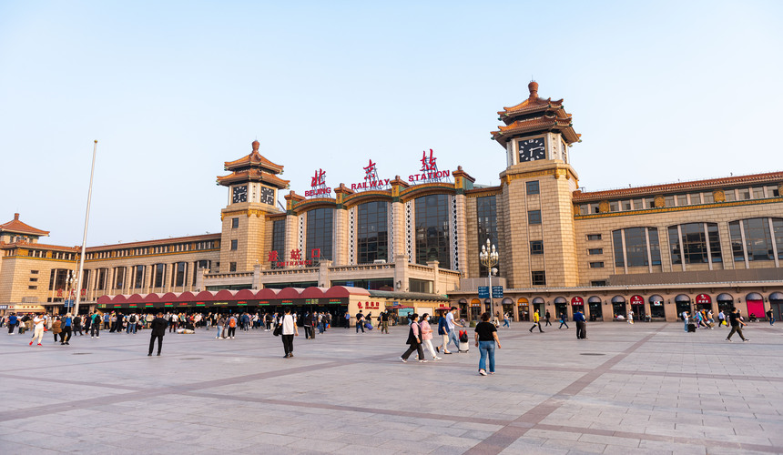Busy scene at Beijing Railway Station with travelers and high-speed trains.