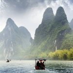 Panoramic view of Guilin’s karst mountains and Li River under a blue sky.
