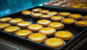 Freshly baked golden egg tarts with flaky crusts on a plate.