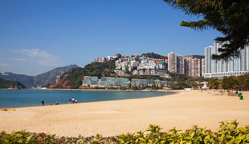  Golden sandy beach and calm waters at Repulse Bay with coastal buildings.
