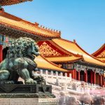 Group of international tourists exploring a historic Chinese landmark with a local guide, surrounded by traditional architecture and scenic views.