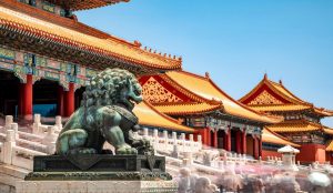 Group of international tourists exploring a historic Chinese landmark with a local guide, surrounded by traditional architecture and scenic views.