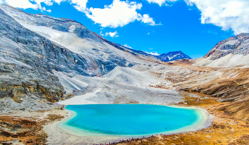 Snow-capped peaks of Daocheng Yading with golden autumn meadows in Sichuan.