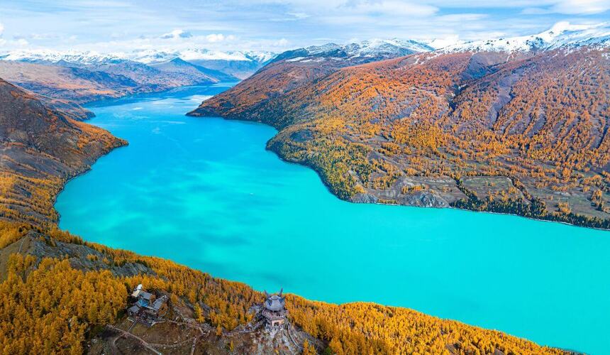 Crystal-clear Kanas Lake in Xinjiang surrounded by autumn-colored forests and mountain reflections.