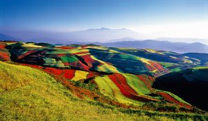 Vibrant red-soil terraces and patchwork farmland in Yunnan Province.