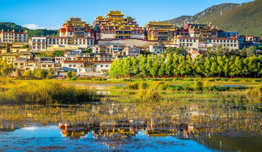 Traditional Tibetan-style town in Shangri-La with prayer flags, monasteries, and mountain scenery.