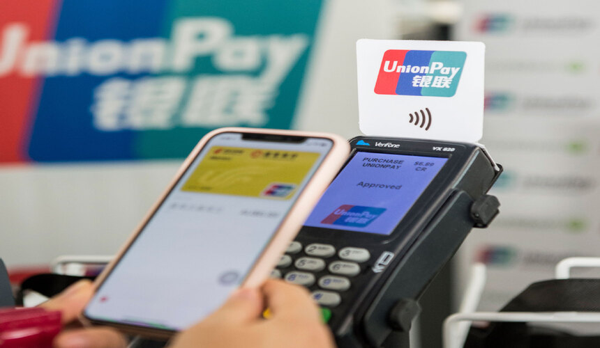 International visitor using a smartphone to make a digital payment at a local market in China.