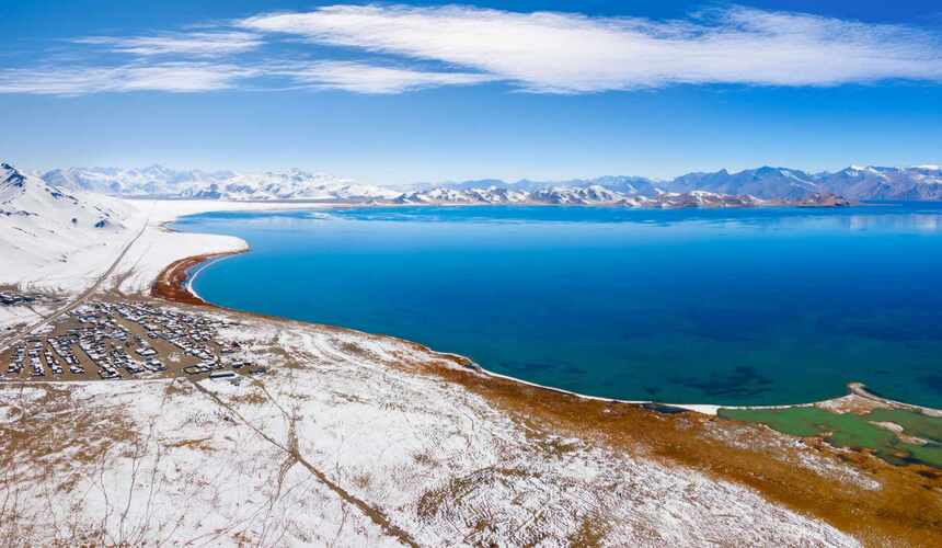 Snow-capped mountains reflected in the crystal-clear waters of Xinjiang Karakul Lake