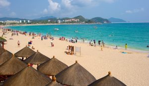 Beachgoers enjoying the tropical shoreline of Dadonghai Beach in Sanya, China