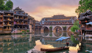 Stilt houses along the Tuojiang River and glowing lanterns in Fenghuang Ancient Town, Hunan, China.