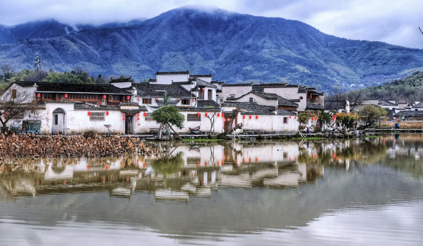Traditional white-walled houses reflected in a peaceful pond in Hongcun Village, Anhui, China.