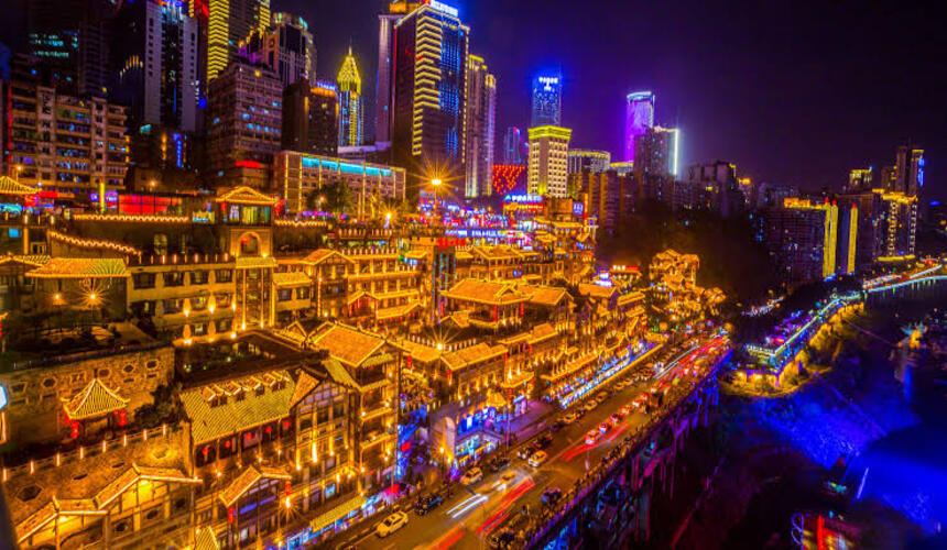 Hongya Cave glowing at night with traditional stilt houses overlooking the Jialing River in Chongqing.